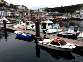 Boats moored at harbor against sky