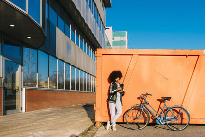 Smiling woman taking selfie through mobile phone during sunny day