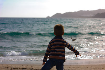 Rear view of boy standing at beach