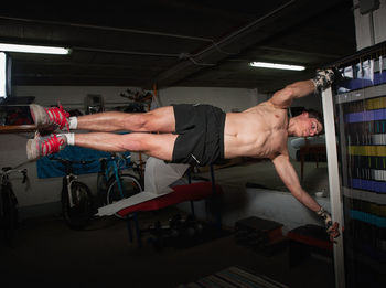 Shirtless man exercising with pole in gym