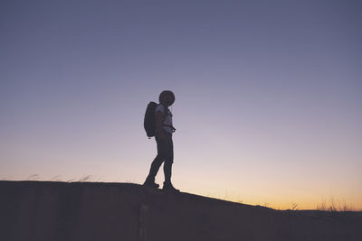 Low angle view of man standing against sky during sunset