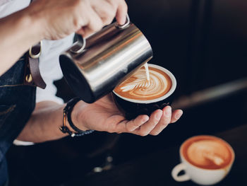 Cropped image of person preparing coffee at cafe