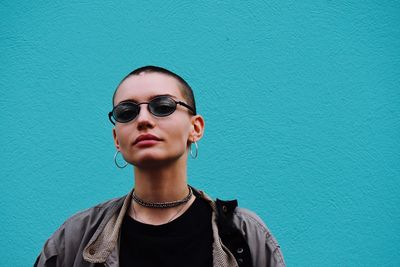 Portrait of woman wearing sunglasses against blue wall