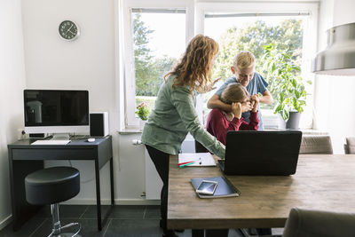 Rear view of women standing on table at home