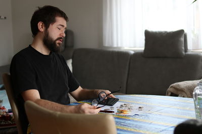 Young man looking away while sitting on sofa at home
