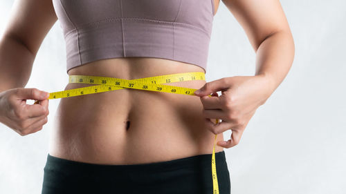 Midsection of woman standing against white background