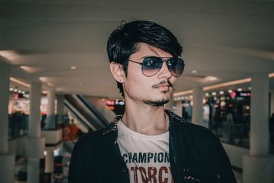 Young man wearing sunglasses while standing in shopping mall