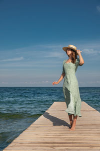 Woman standing on pier over sea against sky