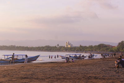 People on beach against sky during sunset