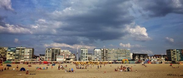 People on beach against cloudy sky