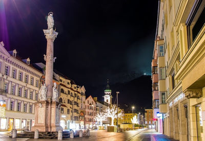 Illuminated street amidst buildings in city at night
