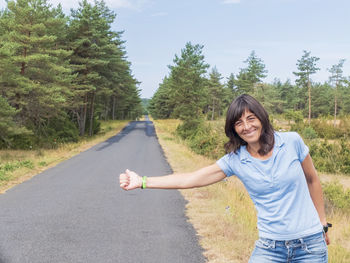 Portrait of smiling young woman standing on road