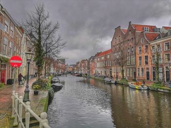 Canal amidst buildings in city against sky