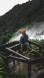 Rear view of man standing by railing against mountain