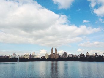 City at waterfront against cloudy sky