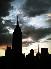 Low angle view of silhouette buildings against cloudy sky