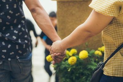 Midsection of couple holding hands standing outdoors