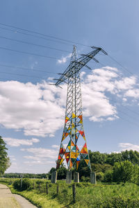 Low angle view of electricity pylon on field against sky