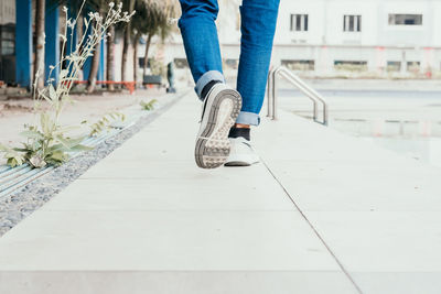 Low section of woman skateboarding on footpath