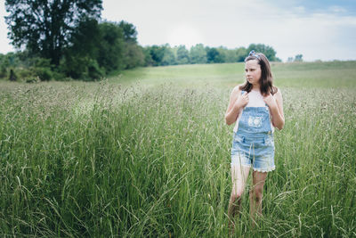 Girl standing in a grassy praire on a summer day.