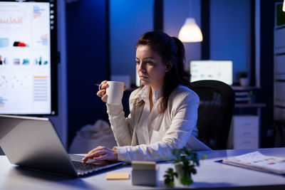 Young woman using phone while sitting on table