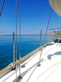 Sailboat sailing in sea against clear blue sky