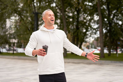 Smiling man holding coffee cup standing outdoors