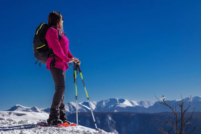 Rear view of man skiing on snowcapped mountain against clear sky