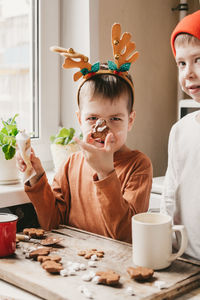 Boys decorate christmas cookies with white icing. children decorate a gingerbread man 