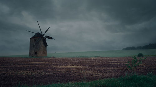 Old abandoned stone mill during the rain in the field