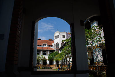 Buildings against sky seen through window