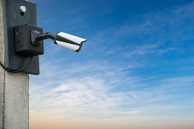 Low angle view of security camera against sky during sunset