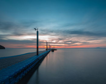 Pier over sea against sky during sunset