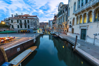 Canal amidst buildings in city against sky