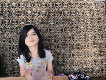 Portrait of a beautiful young woman sitting against wall