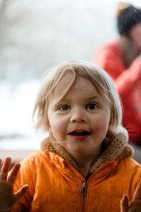 3 year old girl smiles through window at her uncle during quarantine