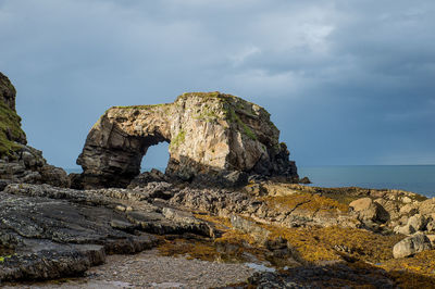 Rock formation in sea against sky