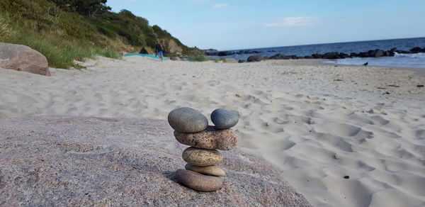 Stack of pebbles on beach against sky