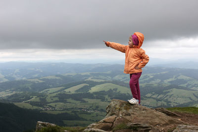 Rear view of man standing on mountain against sky