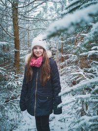 Portrait of smiling girl standing amidst trees during winter