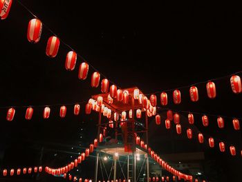 Low angle view of illuminated lanterns hanging against sky at night