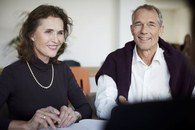 Smiling senior woman sitting with man during meeting at law firm