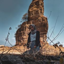 Full length of woman standing on rock against sky