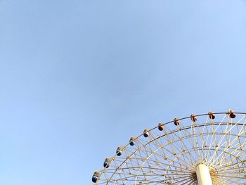 Low angle view of ferris wheel against clear blue sky