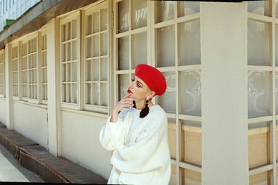 Young woman using mobile phone while standing against building