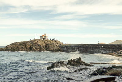 Lighthouse by sea against sky