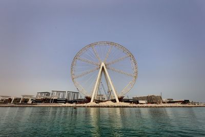 Ferris wheel by sea against clear sky