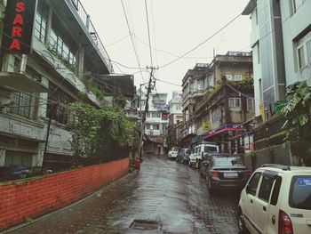 Wet street amidst buildings in city during rainy season