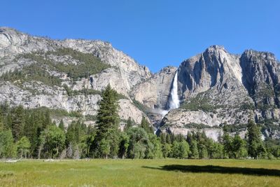 Scenic view of trees and mountains against clear blue sky