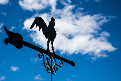 Low angle view of birds perching on weather vane